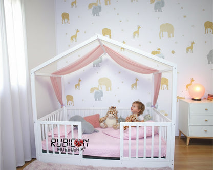 Cama Montessori casita de madera natural con barandales y dosel rosa. Ideal para habitación infantil.